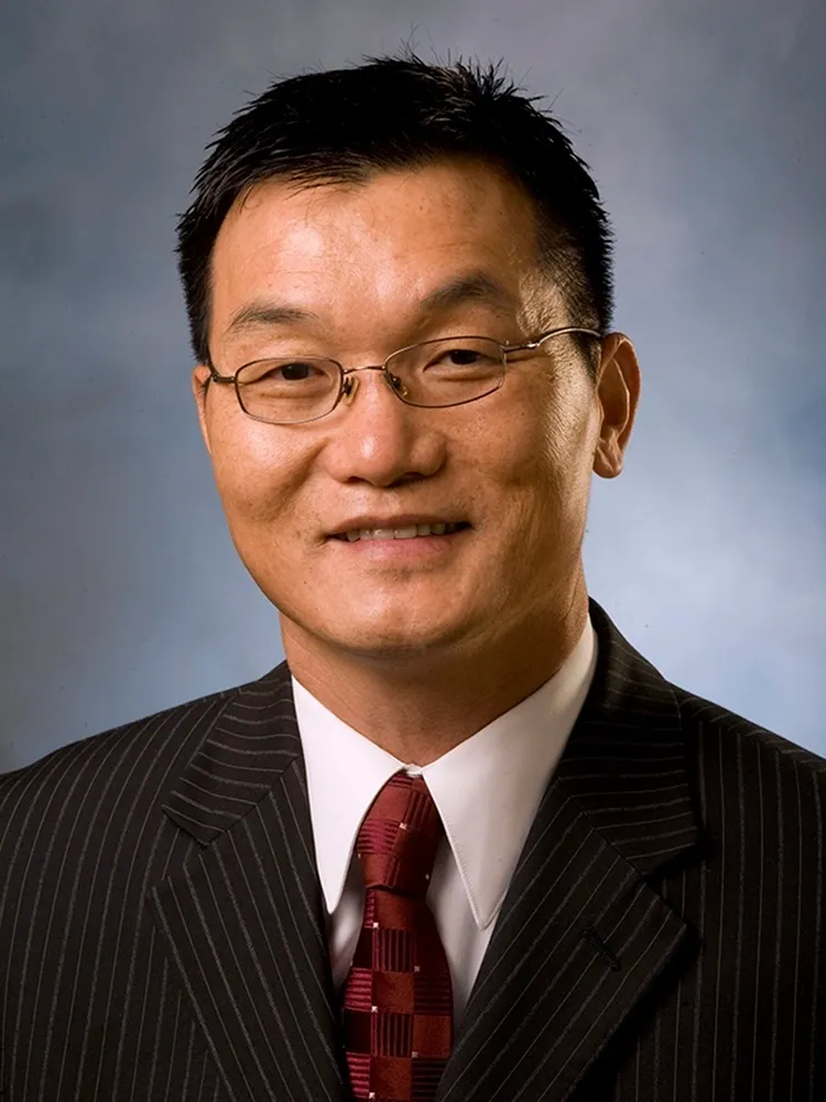 A man in a suit and tie smiling for the camera.