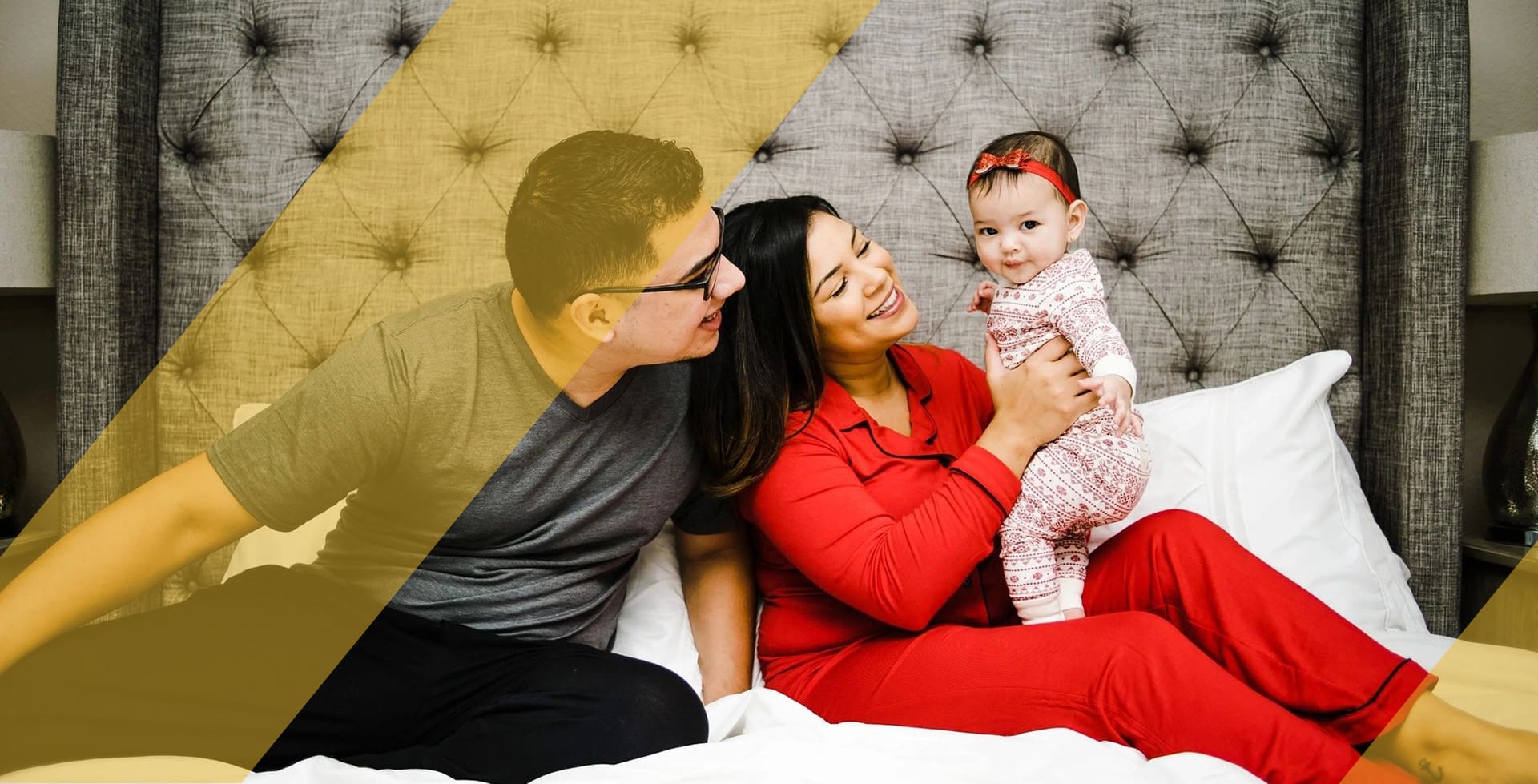 A man and woman holding a baby on top of a bed.