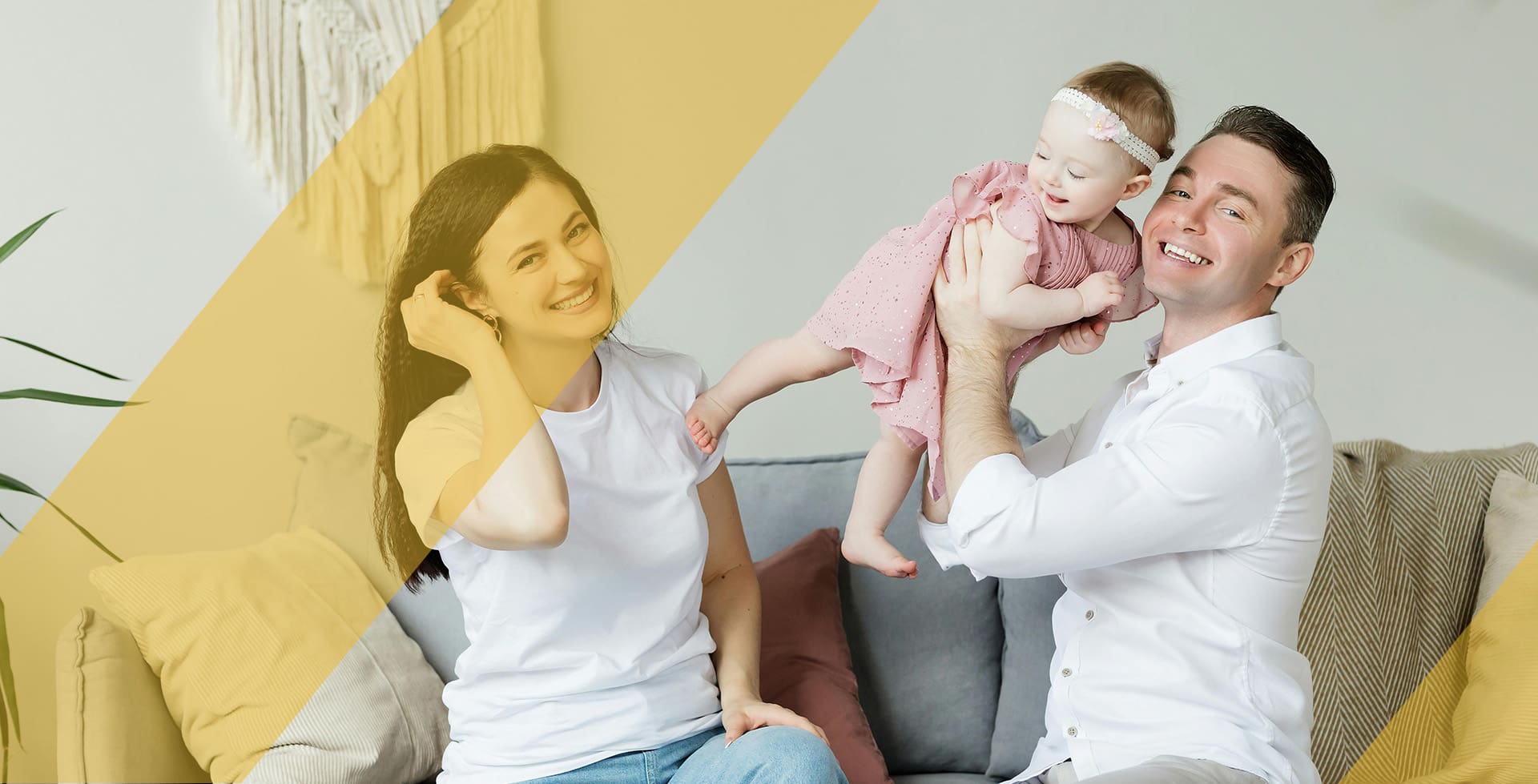 A woman and man holding a baby on the couch