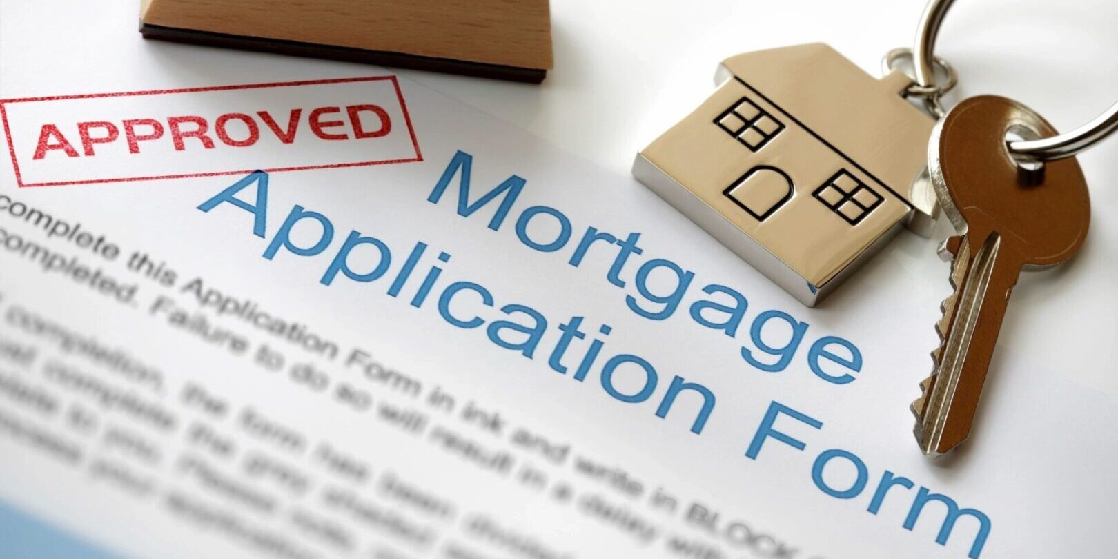 A mortgage application form with a stamp and house key.