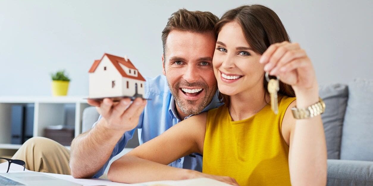 A man and woman holding keys to their new home.